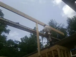 Carpenter setting a ridge beam over a new addition frame — Ice Dam Removal by Roofing Brothers in Canastota