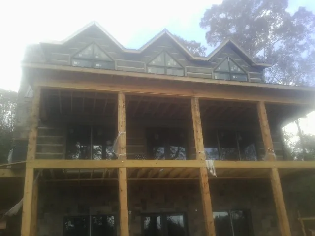 Dormers and porch framing on a large log home under construction — Roof Coating work by our crew in Canastota