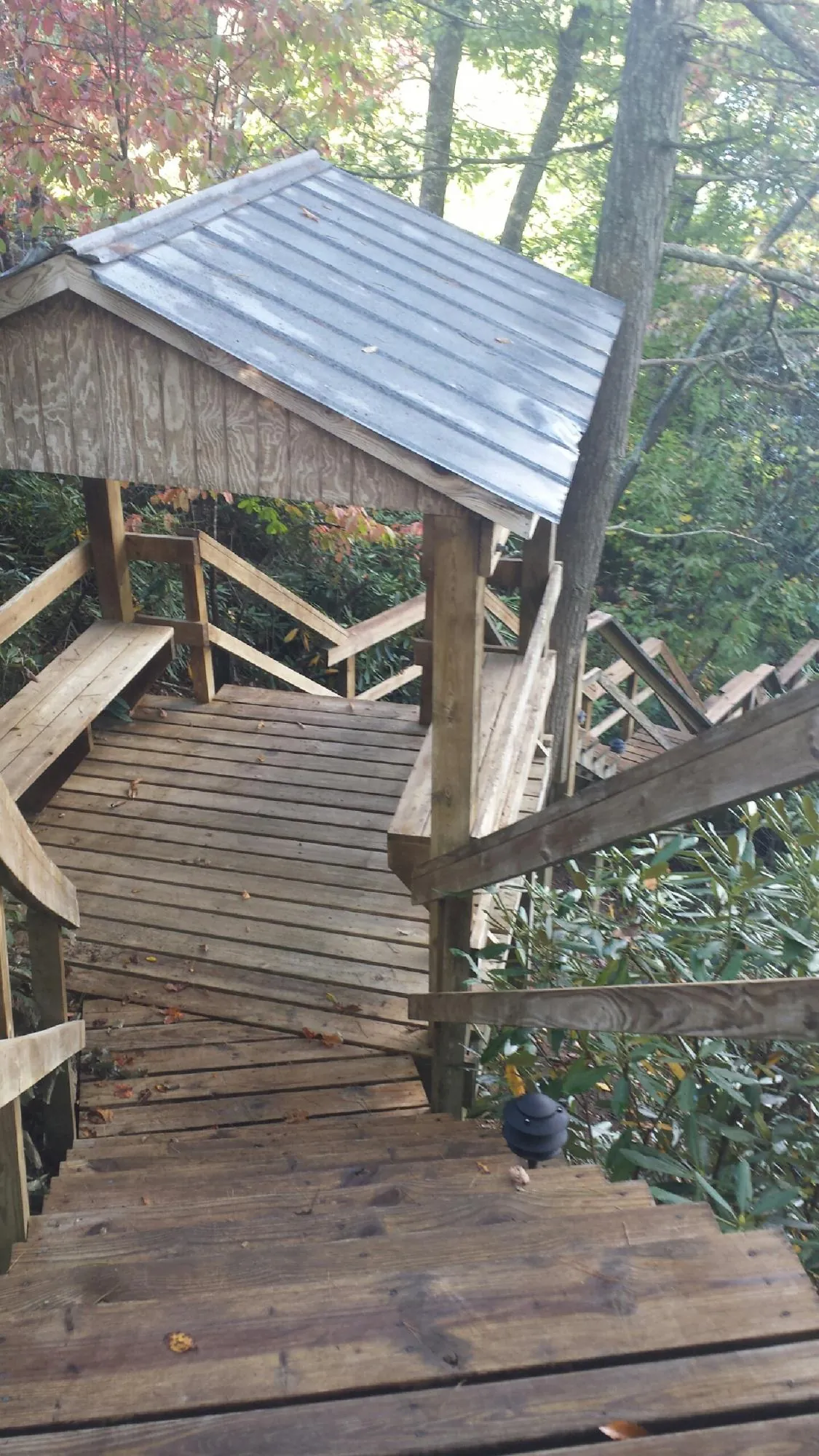Metal roofed shelter over wooden steps on a wooded walkway — Skylight Repair & Installation work by our crew in Canastota