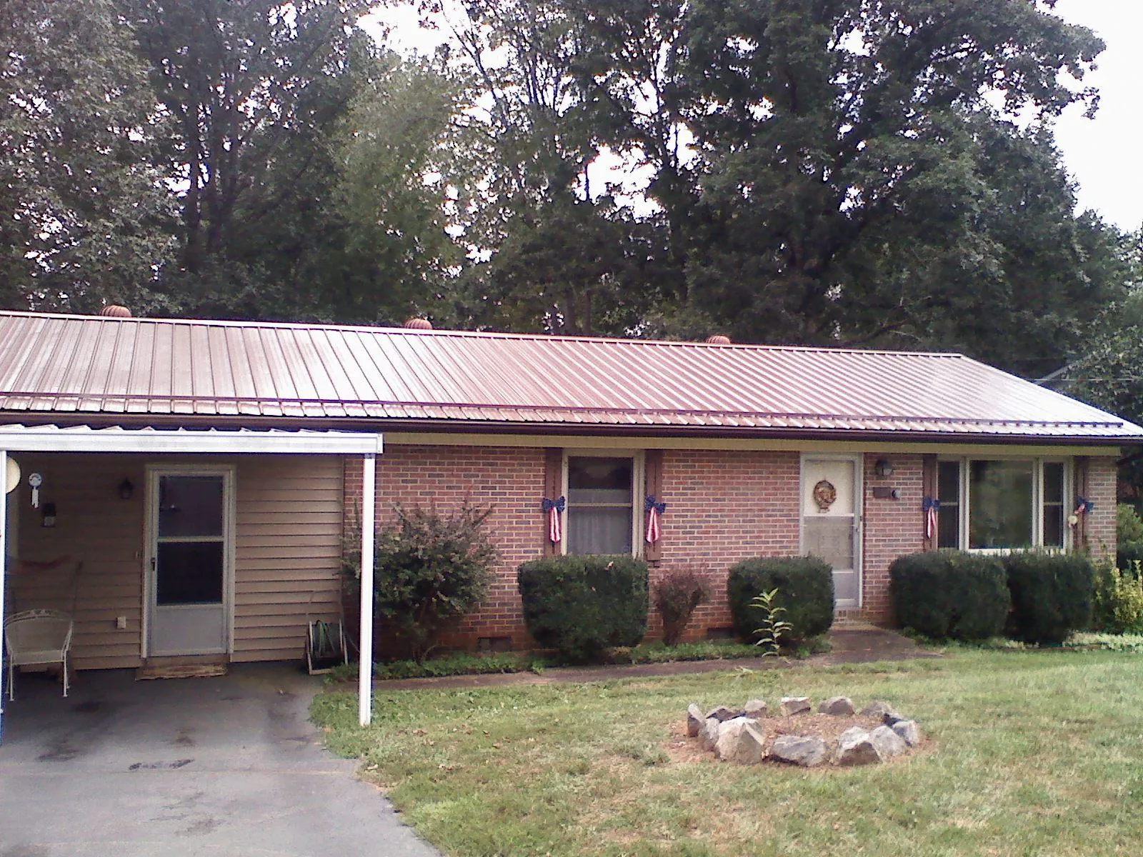 Bronze metal roof and carport on a brick ranch home — Roof Repair work by our crew in Canastota